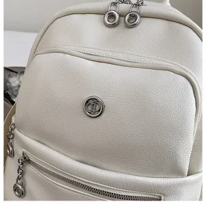 White faux leather backpack detail showcasing metal ring zippers and front pocket design.