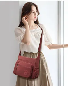 Detail shot of multi-pocket nylon crossbody bag with secure zipper compartments and strap.