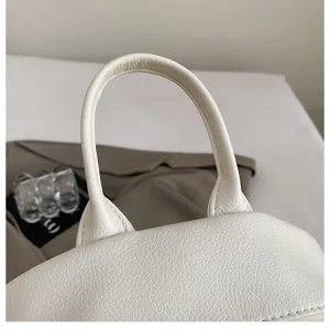 White leather backpack detail view showing handle and premium texture for daily commute style.