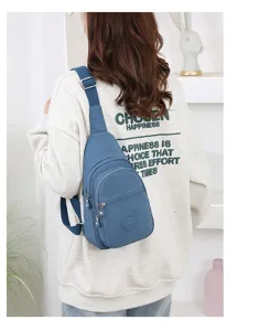 Detailed lifestyle view of a blue nylon sling chest bag worn by a model in a clean indoor setting.