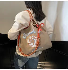 Detail view of a stylish nylon tote bag with sweet donut embroidery and colorful rope straps.