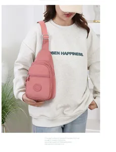 Detailed view of the pink nylon chest bag worn by model, showing zipper pocket and strap.