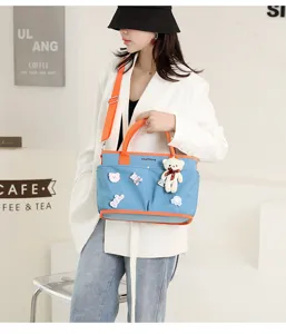 Detail view of large capacity diaper bag with cute bear pendant, stylish mommy tote for travel.