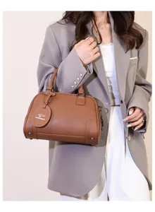 Detailed view of the brown leather Boston handbag with top handle and kangaroo tag accessory.