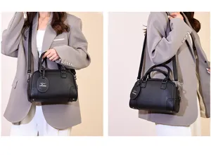 Detail view of the stylish black leather Boston handbag featuring top handles and a shoulder strap.