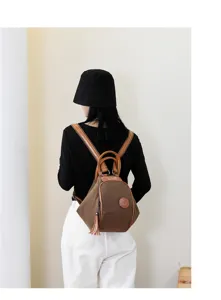 Detail view of the stylish brown canvas backpack with leather trim and tassel accent.