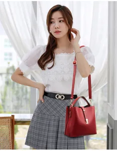 Red soft leather bucket bag detail showing metal lock closure and adjustable strap for women.