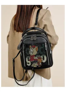 Detail view of a black soft leather backpack with rhinestone cartoon and letter design.