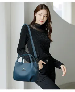Detailed shot of the blue leather handbag featuring a metal logo and spacious design.