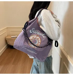 Detail view of purple nylon tote bag with cute donut embroidery and thick rope straps.