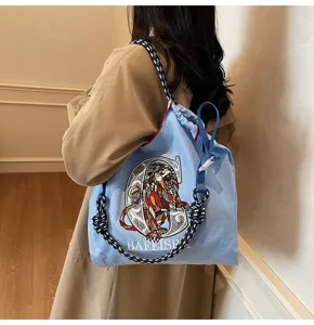 Canvas shoulder bag detail showing embroidered lion pattern and drawstring closure.