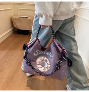 Close-up of stylish embroidered nylon tote bag with rope handle and donut graphic detail.