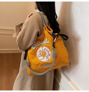 Detail view of Japanese style nylon tote bag with sweet donut embroidery and shoulder strap.