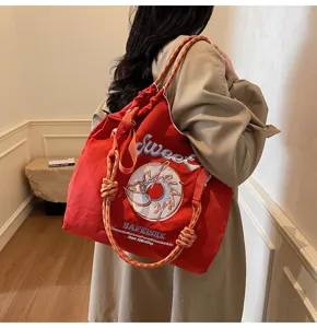Red nylon tote bag detail showing embroidered donut graphic and stylish slogan lettering.