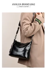 Vintage black leather shoulder bag for women, stylish commuting bucket bag with wide strap.