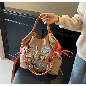 Close-up detail of embroidered canvas tote bag with Paris theme and red rope handles.