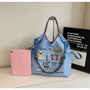 Detail view of blue nylon canvas tote bag featuring exquisite Paris themed landmark embroidery.