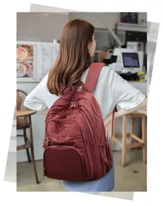 Stylish maroon multi-pocket nylon backpack in a café setting, showcasing dual shoulder straps.