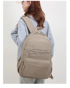 Vista dettagliata di uno zaino in nylon leggero con tasche multiple indossato da una modella.
