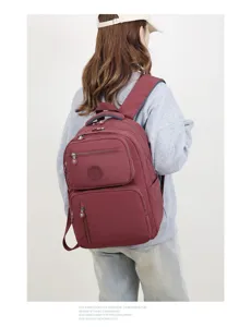 Vista dettagliata dello zaino bordeaux a scomparti multipli indossato dalla modella di spalle.