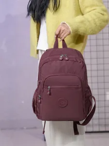 Vista di dettaglio dello zaino casual in nylon rosso scuro con tasche multiple e zip.