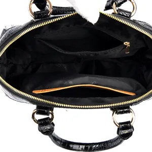 Black patent leather top handle shell bag with spacious interior compartment and gold hardware.
