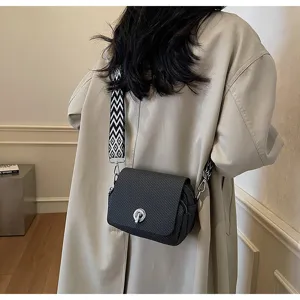 Detail shot of women's black woven mini crossbody bag with chic geometric wide strap.