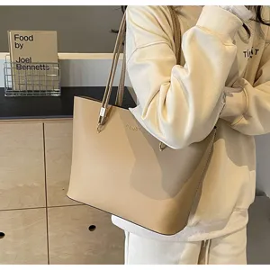 Close-up detail of minimalist beige leather tote bag shoulder strap and metal hardware.