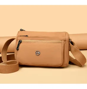 Details of solid color nylon crossbody shoulder bag, khaki commuter bag with multi zippers.