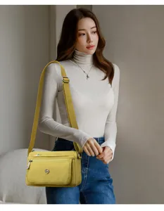 Detailed view of yellow canvas crossbody bag with wide strap and multi zipper pockets.
