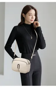 Detailed view of the soft leather crossbody bag with double zippers and metal buckle design.