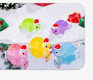 Close-up shot of luminous resin turtles with cute Santa hats, glowing in dark desktop decor.