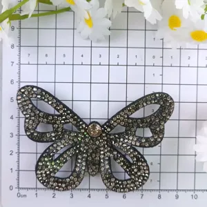 Rhinestone butterfly patch detail view on measuring grid, sparkly DIY shoe and hair accessory.