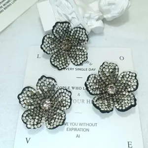 Nahaufnahme handgemachter Strass-Blumenfugen, glitzernde Kristalle auf schwarzer Basis.
