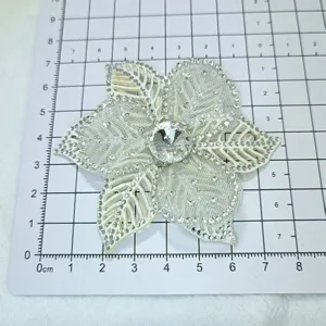 Gros plan de detail de patch de dentelle de fleur en organza blanc 3D avec strass central.