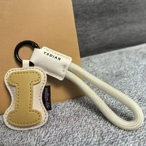 Close-up detail of the leather letter keychain and braided wrist strap with metal hook.