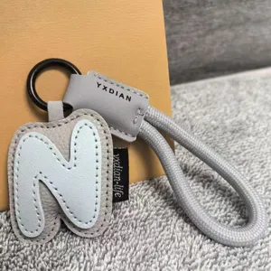 Letter N leather keychain with grey braided strap, stylish dopamine bag pendant accessory.