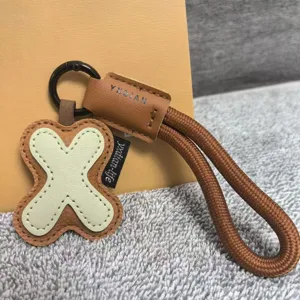 Leather letter X keychain detail, brown woven strap, cute dopamine bag pendant accessory.