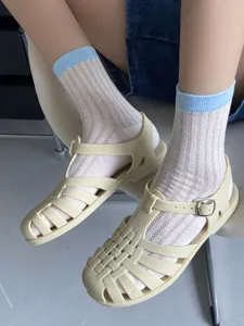 Nahaufnahme von lässigen Damen Strick Socken kombiniert mit stilvollen sommerlichen Sandalen.