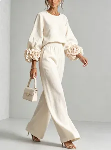 Primo piano dell'elegante set crema con polsini floreali 3D drammatici e pantaloni larghi alla moda.