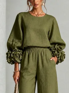 Vista dettagliata del elegante completo verde con polsini floreali e pantaloni lunghi.