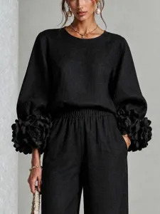 Elegante completo nero a due pezzi con top a manica lunga e polsini floreali alla moda.