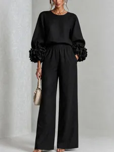 Elegante completo nero da donna con top a maniche lunghe con dettagli floreali e pantaloni larghi