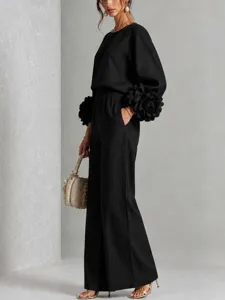 Elegante completo nero con top a maniche lunghe e pantaloni larghi con polsini floreali.