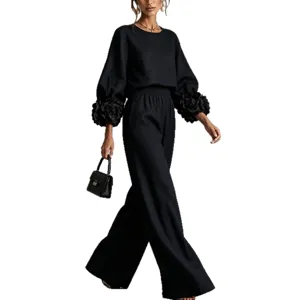 Elegante completo nero a due pezzi con polsini floreali vistosi e pantaloni ampi eleganti.