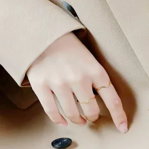 Anello sottile ondulato in acciaio dorato, primo piano dettaglio, stile minimal chic