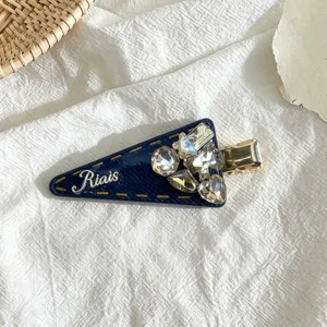 Detailed shot of sparkling rhinestone triangle hair clip with stylish blue fabric design.