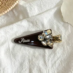 Detail of vintage dark brown triangle hair clip with rhinestones and elegant metallic design.