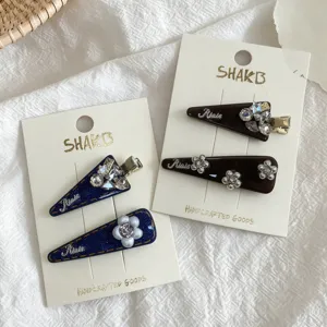 Detail view of vintage rhinestone geometric triangle hair clips set with elegant denim texture.