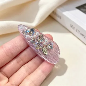 Detailed view of a Korean style pink resin hair clip adorned with sparkling heart rhinestones and pearls.